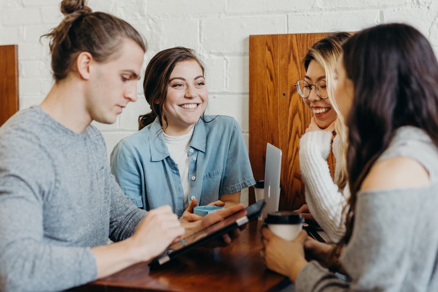 Vier jonge mensen praten en lachen samen aan een tafel