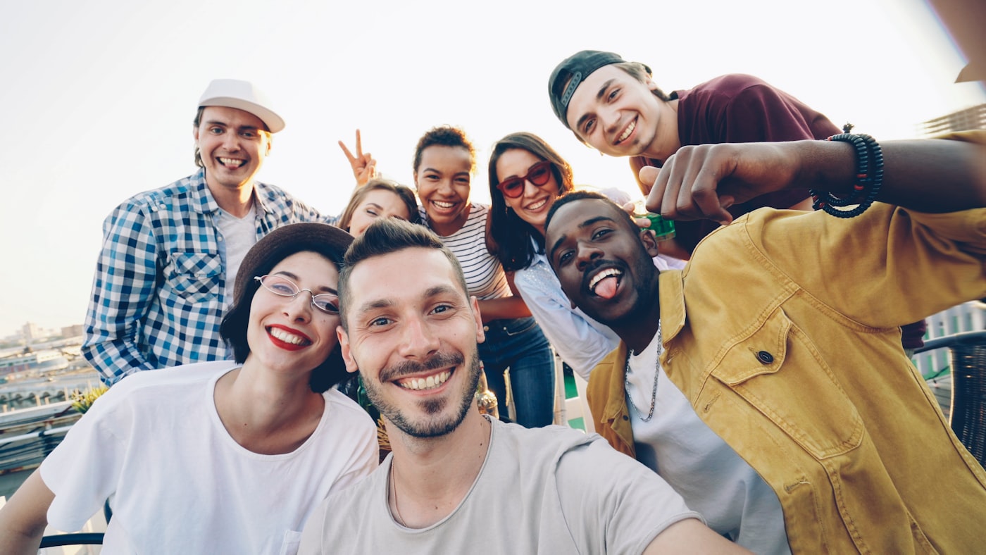 A diverse group of young people laughing together on a rooftop in the city